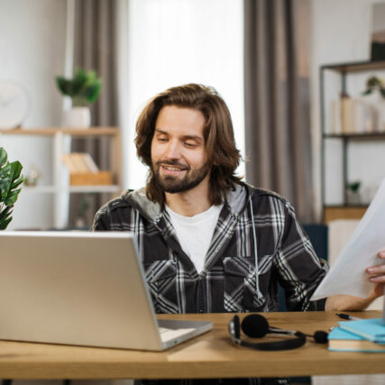 Caucasian man presenting financial report to colleagues through video call on laptop. Male freelancer sitting at workplace and talking with client.